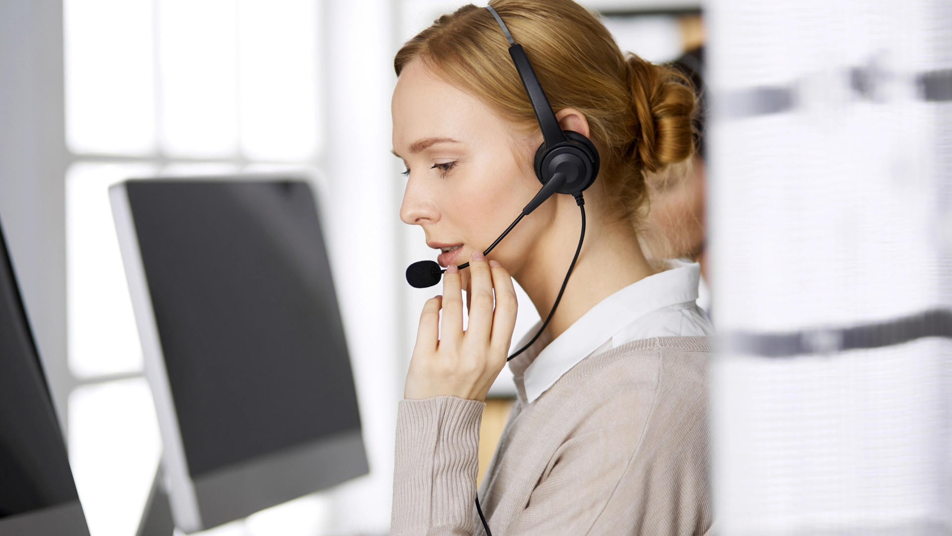 Customer service representative wearing a headset, focused on assisting a customer.