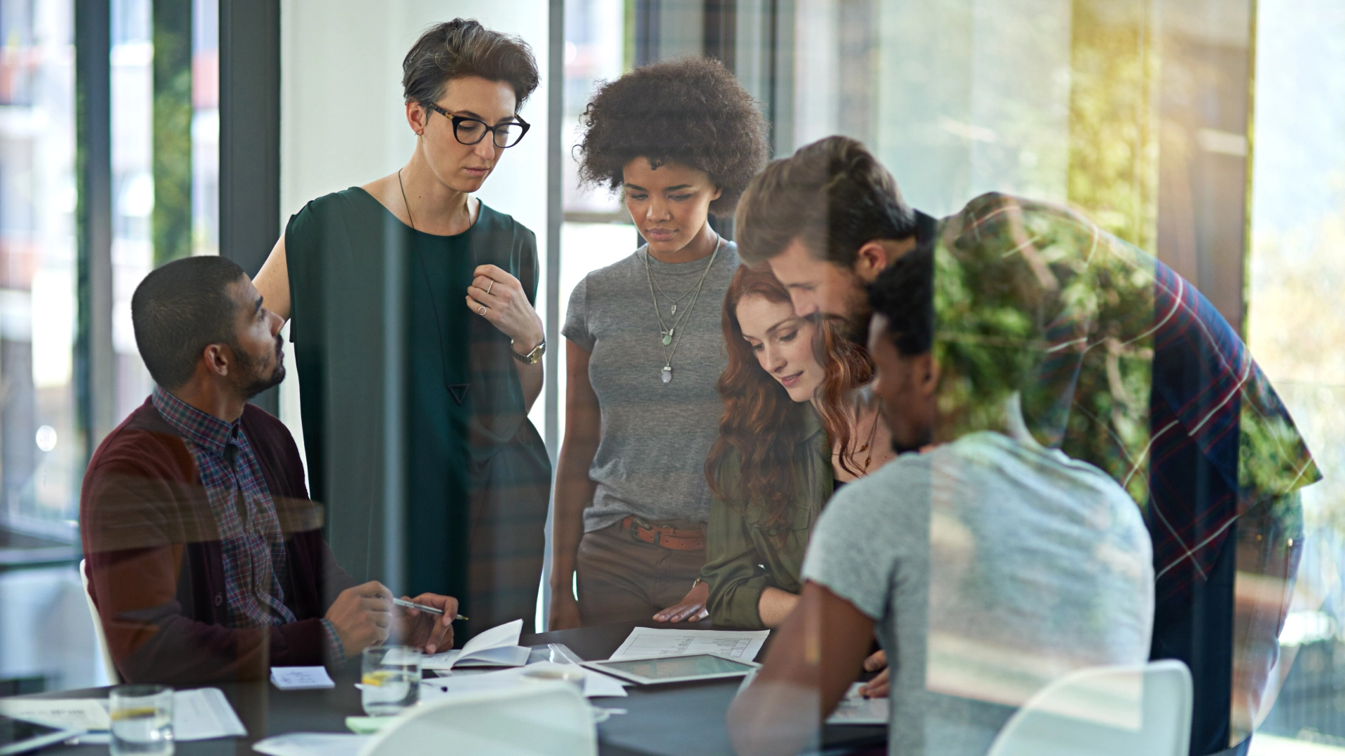 Colleagues gathered at a table, sharing ideas and reviewing documents in a bright office space.