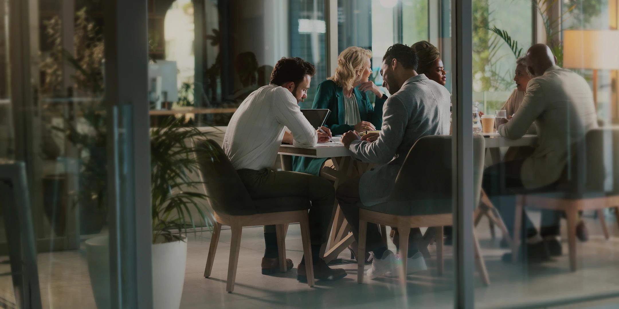 Group of professionals in a modern office gathered around a conference table during a meeting.