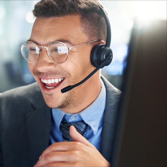 Close-up of a smiling customer support agent in a suit and headset.