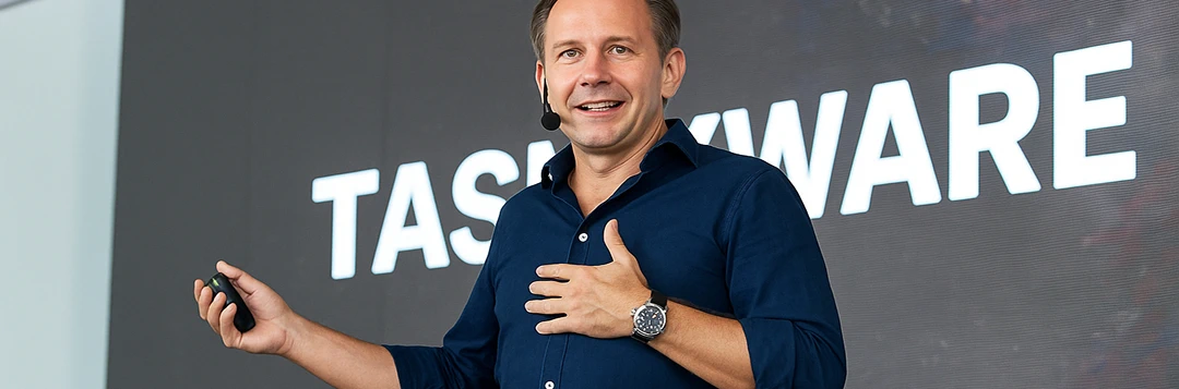 Bir konferansta konuşan mavi gömlekli bir adam