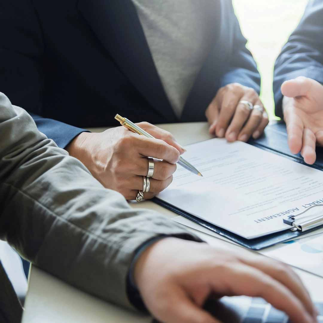 Close-up of a hand signing a contract agreement with a gold pen