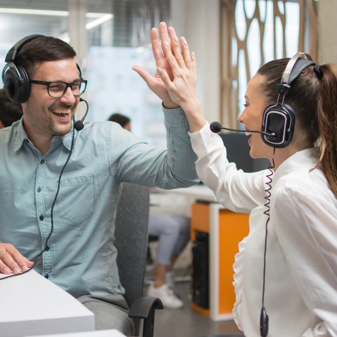 Two call center agents high-fiving, celebrating a successful outcome