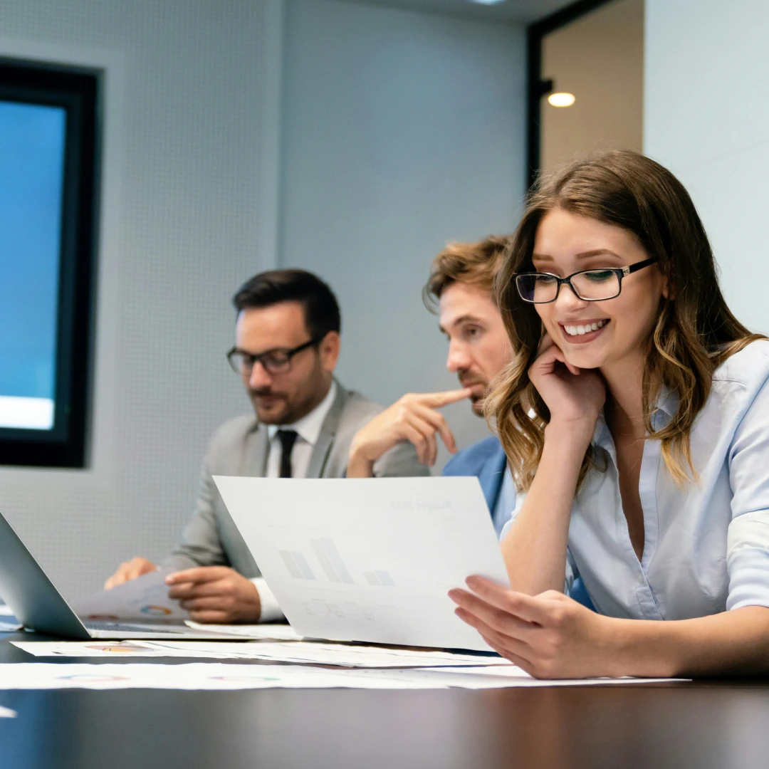 Smiling business woman reviewing documents during a meeting with colleagues