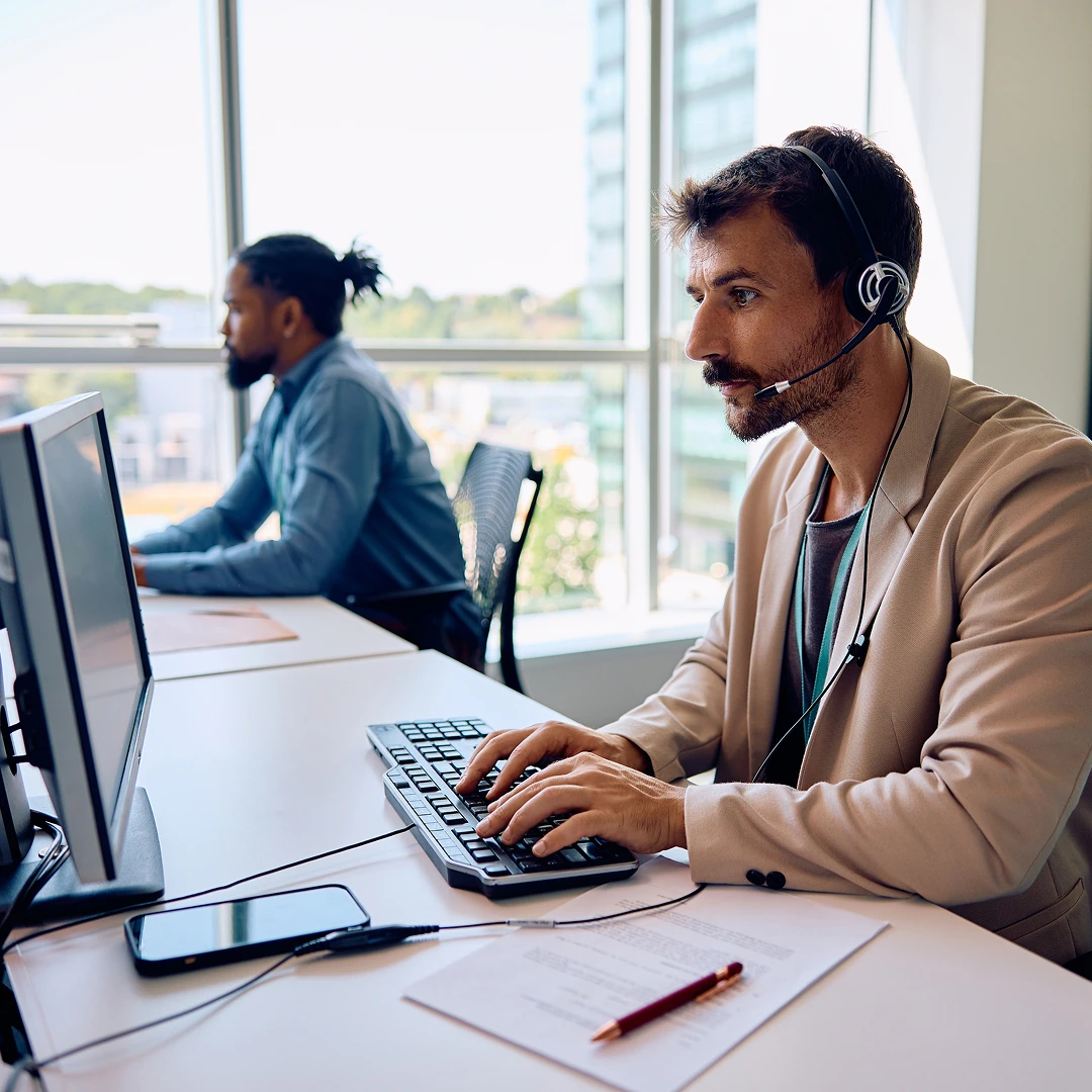 Two customer support representatives wearing headsets, working in a modern and spacious call center in Boston