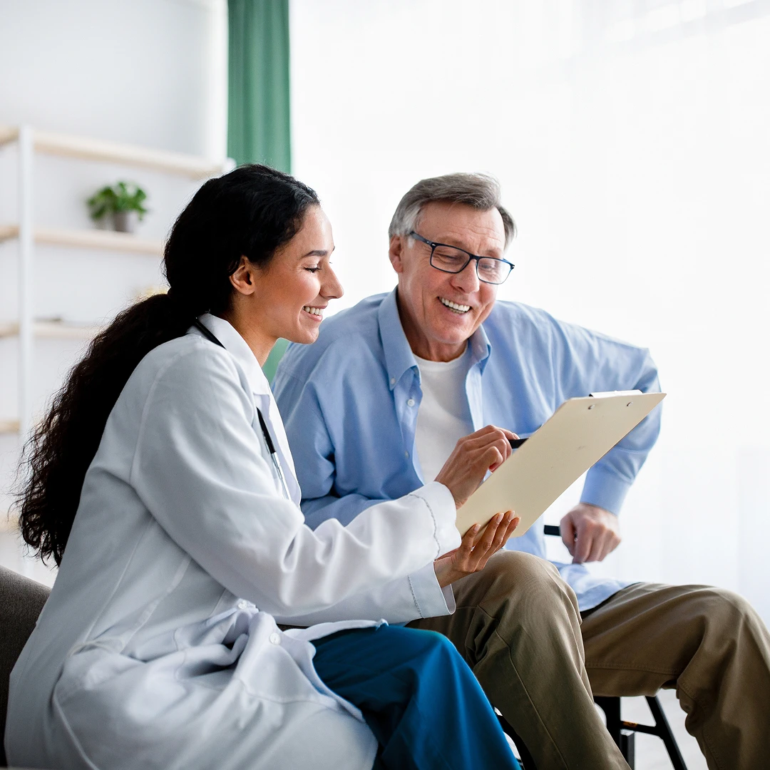 A cheerful doctor reviews medical information with a happy senior man, creating a positive and supportive healthcare experience