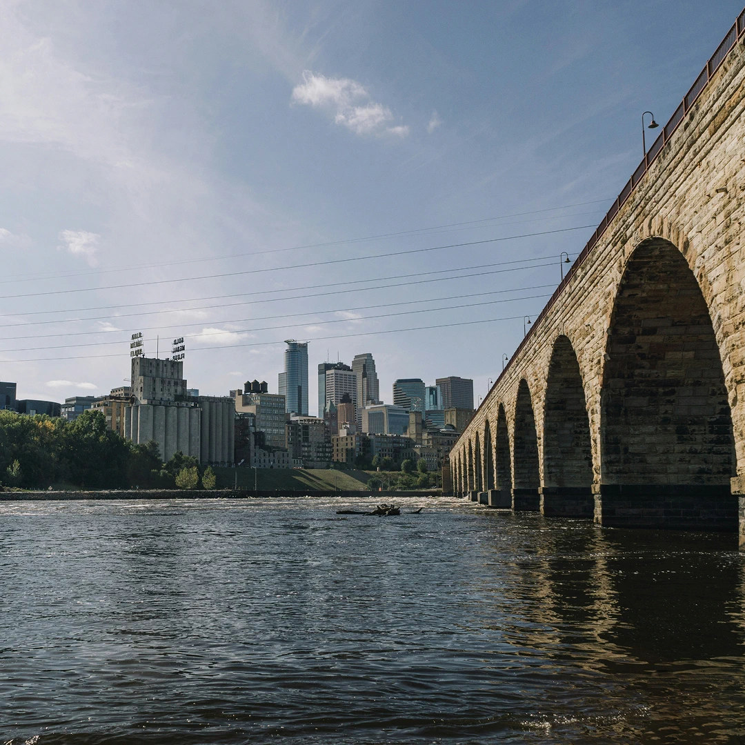 Minneapolis skyline and the Stone Arch Bridge, with the Mississippi River in the foreground