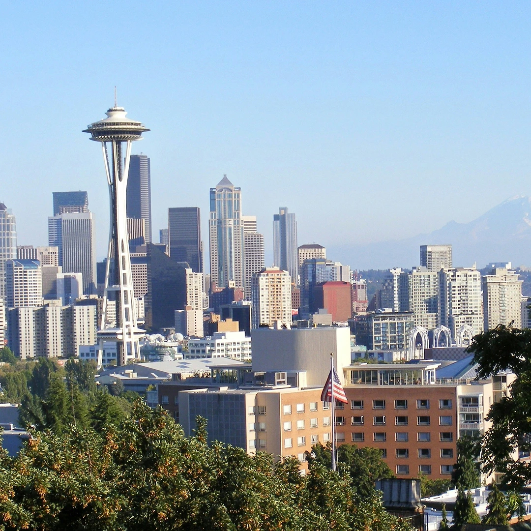 The Seattle skyline includes the iconic Space Needle set against skyscrapers and a blue sky
