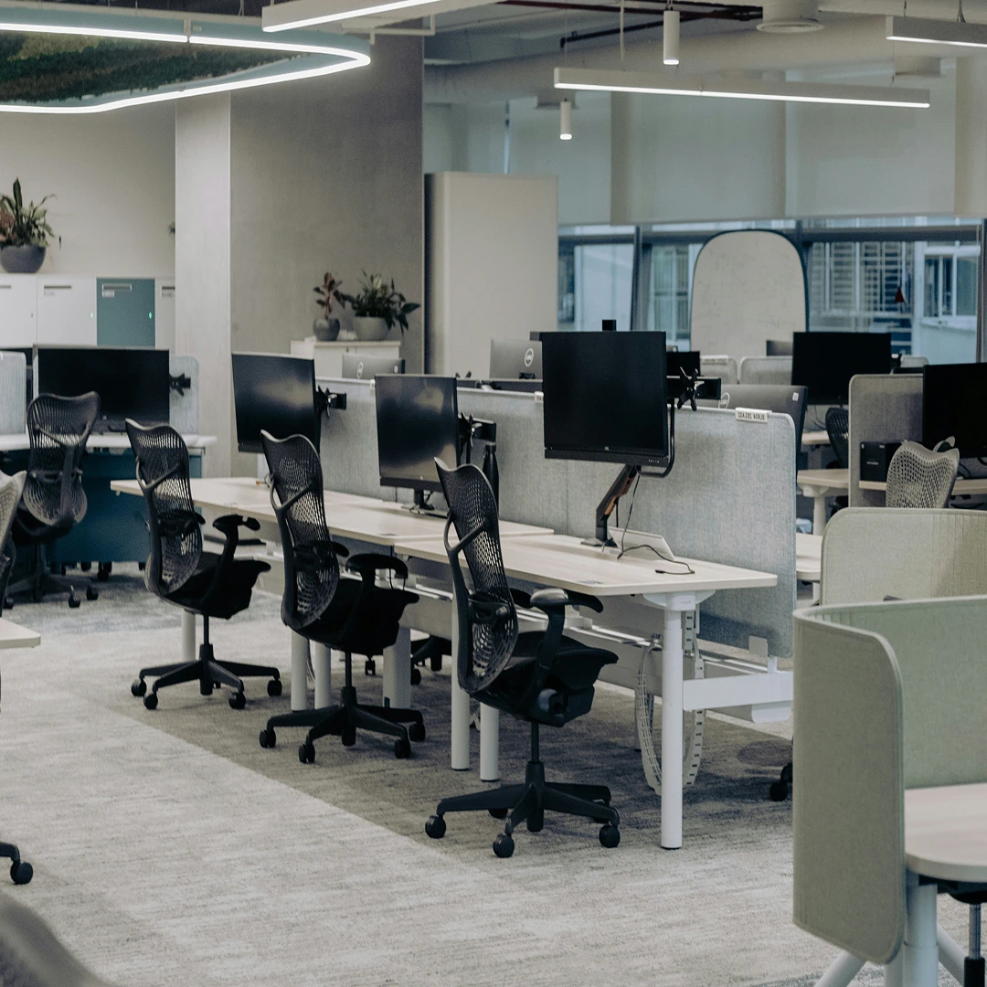 Modern, well-lit office space with rows of desks and ergonomic chairs
