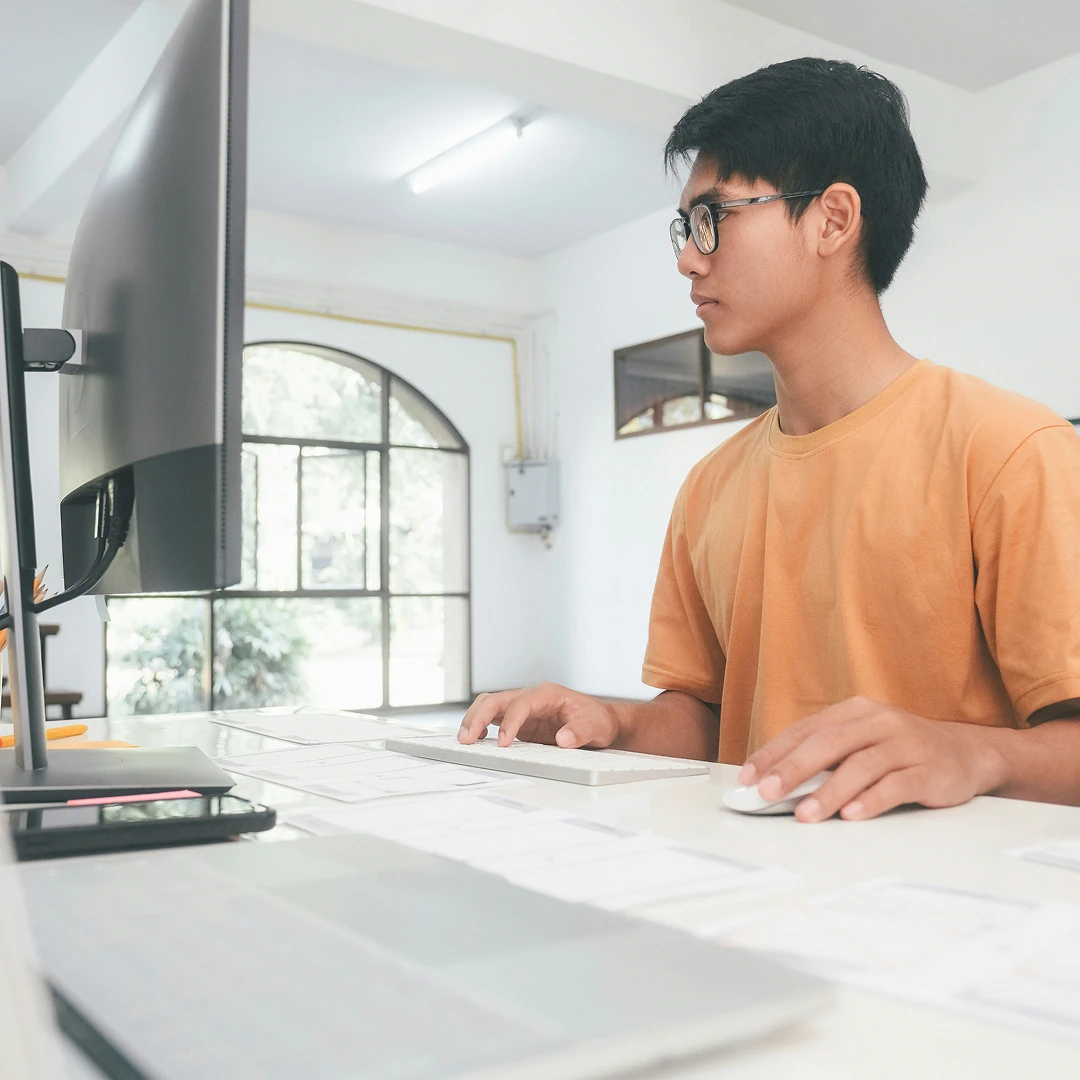 Healthcare customer support representative wearing an orange t-shirt, working at a workstation