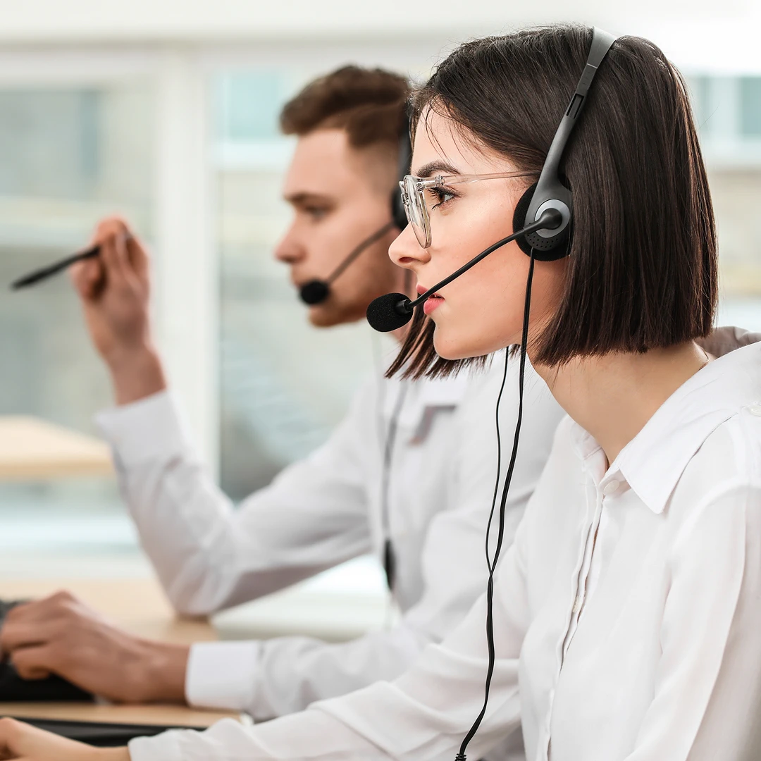Man and woman wearing white shirts and headsets working in a bright modern office