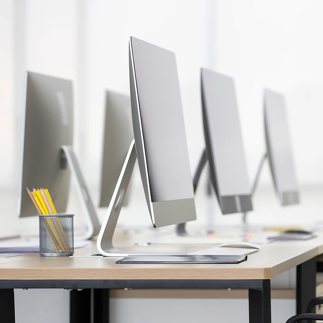 Office space with workstations equipped with silver desktop computers and a pencil holder
