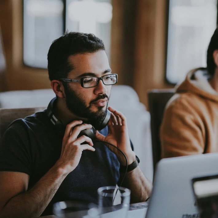 a bearded customer support manager either putting off or putting on his headphones (ready to assist customers in trouble)