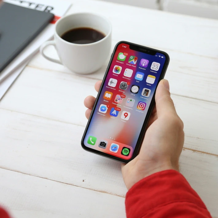 a guy holding an iphone, coffee on a table, life is good