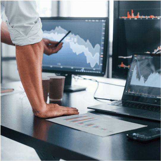 a man standing with a pen in front of a screen with some graph